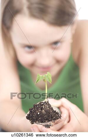 Stock Photograph - 9 year old girl with small plant on garden spade. Fotosearch
