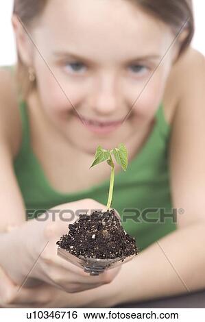 Stock Photograph - 9 year old girl with small plant on garden spade. Fotosearch