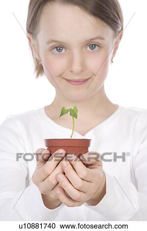 Stock Image - 9 year old girl with small potted plant in her hands. Fotosearch