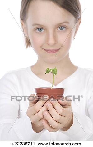 Stock Image - 9 year old girl with small potted plant in her hands. Fotosearch
