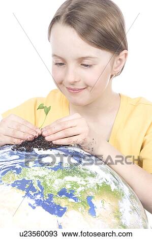 Stock Image - 9 year old girl with the small plant on the globe. Fotosearch