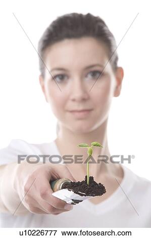 Stock Photo - face of a young woman with a spatula and small plant. Fotosearch