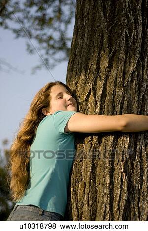 Stock Photo - Twelve year old girl hugging large tree in Assiniboine Park, Winnipeg, Canada. Fotosearch