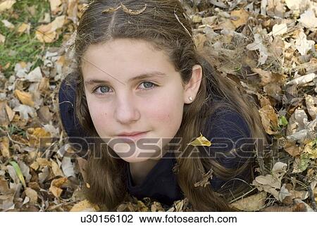 Stock Image - Girl lying in leaves, Winnipeg, Canada. Fotosearch