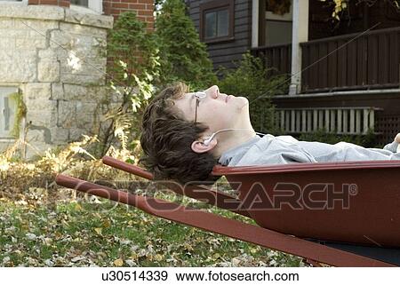 Stock Photo - Teen boy listening to music in wheelbarrow, Winnipeg, Canada. Fotosearch