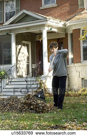 Stock Photo - Teen boy listening to music while raking, Winnipeg, Canada. Fotosearch