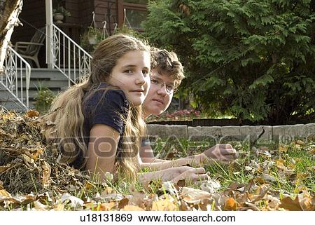Stock Photo - Teen brother and sister lying in leaves viewed from the side, Winnipeg, Canada. Fotosearch