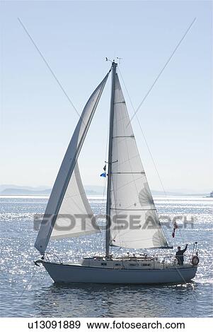 Stock Photo - A sailboat passes by the Sidney waterfront, Sidney, BC. Fotosearch