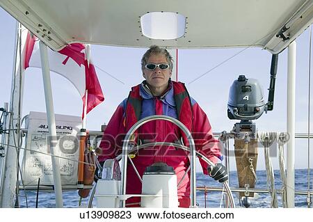 Stock Image - Man at the helm of a sailboat off the coast of California near San Francisco. Fotosearch