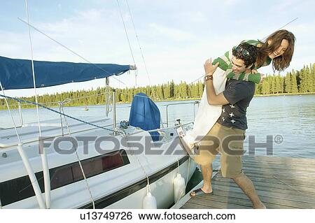 Stock Photograph - Playful couple beside boat, Clear Lake, Riding Mountain National Park, Manitoba, Canada. Fotosearch