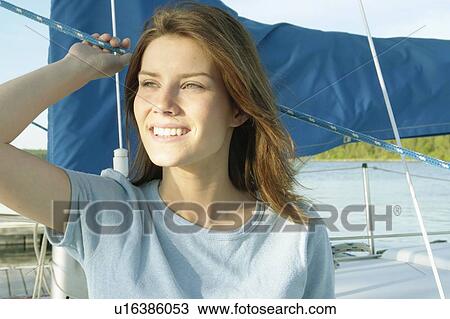 Stock Image - Young woman wearing hemp shirt on sail boat, Clear Lake, Riding Mountain National Park, Manitoba, Canada. Fotosearch