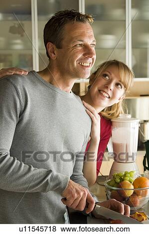 Stock Photo - Couple cutting organic fruit for smoothie, Winnipeg, Canada. Fotosearch