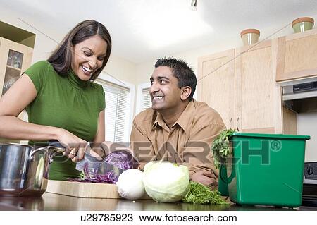 Stock Image - Couple in kitchen cutting vegetables beside kitchen compost bin, Winnipeg, Canada. Fotosearch