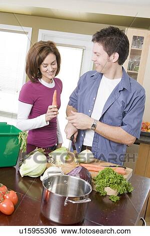 Stock Photograph - Couple in kitchen cutting vegetables beside kitchen compost bin, Winnipeg, Canada. Fotosearch