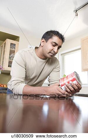 Stock Photo - Man reading ingredients on can, Winnipeg, Canada. Fotosearch