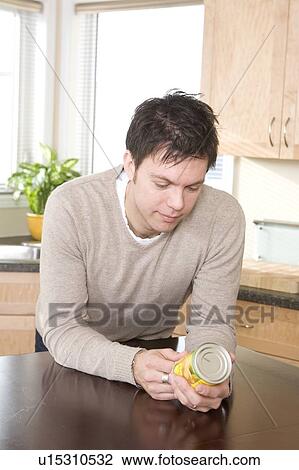 Stock Image - Man reading nutritional information labelling on can, Winnipeg, Canada. Fotosearch