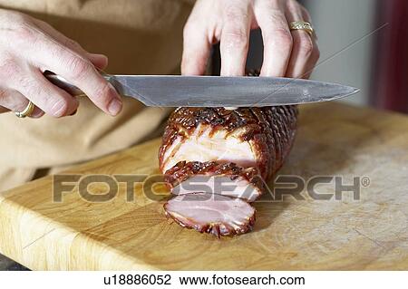 Oven roasted ham being sliced on cutting board with large knife View Large Photo Image Stock Image - Oven roasted ham being sliced on cutting board with large knife. Fotosearch