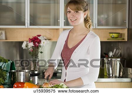 Stock Photography - Woman cutting vegetables, with green kitchen compost pail for collecting kitchen scraps, Winnipeg, Canada. Fotosearch