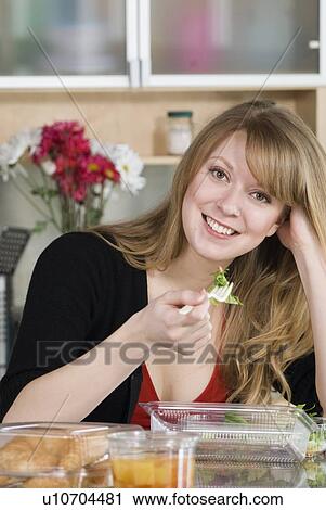 Stock Image - Woman eating take out food from containers and spoon made from corn, and which are fully compostable, Winnipeg, Canada. Fotosearch