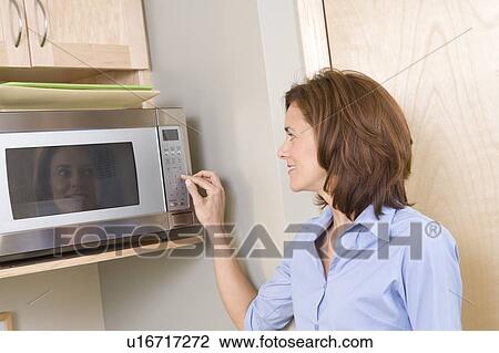 Stock Image - Woman in front of microwave, Winnipeg, Canada. Fotosearch