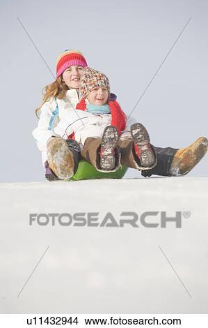 Picture - 13 and 9 year olds slide down hill, Winnipeg, Canada. Fotosearch