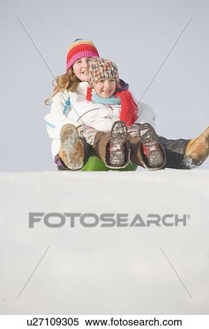 Stock Photography - 13 and 9 year olds slide down hill, Winnipeg, Canada. Fotosearch