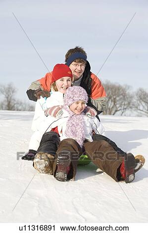 Stock Image - 15, 13 and 9 year olds prepare to slide down hill, Winnipeg, Canada. Fotosearch