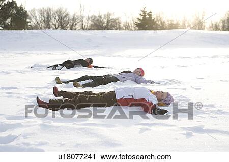 Stock Image - 3 kids, (14, 13, and 9 years old) lying on snow, making snow angel, Winnipeg, Canada. Fotosearch