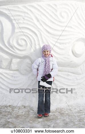 Stock Image - 9-year old girl with skates beside snow sculpture, The Forks, Winnipeg, Canada. Fotosearch