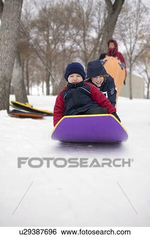 Stock Photograph - Gril pushes another child on toboggan, Regina, Saskatchewan, Canada. Fotosearch