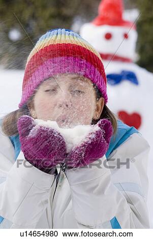 Stock Image - Thirteen year old girl blowing snow toward camera, Winnipeg, Canada. Fotosearch