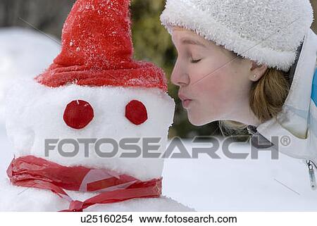 Picture - Thirteen year old girl offers a kiss to a snowman, Winnipeg, Canada. Fotosearch