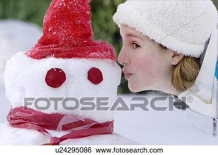 Stock Photograph - Thirteen year old girl offers a kiss to a snowman, Winnipeg, Canada. Fotosearch