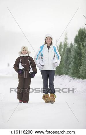 Stock Image - Two girls (9 and 13) with skates walking along frozen Assiniboine River skating trail, Winnipeg, Canada. Fotosearch