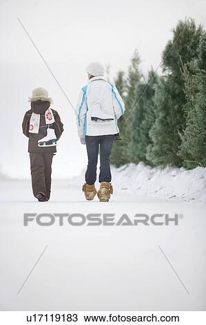 Stock Image - Two girls (9 and 13) with skates walking along frozen Assiniboine River skating trail, Winnipeg, Canada. Fotosearch