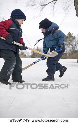 Two young children playing in snow with hockey sticks, Regina, Saskatchewan, Canada View Large Photo Image Stock Photo - Two young children playing in snow with hockey sticks, Regina, Saskatchewan, Canada. Fotosearch