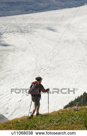 Stock Photo - Woman (20-25) hiking on a ridge above a large Icefield, Parker Ridge, Jasper National Park, Alberta, Canada. Fotosearch