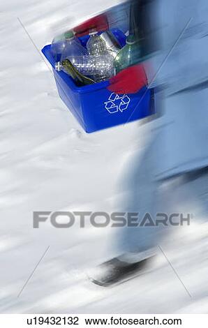 Stock Image - Homemaker taking out "Blue Bin" full of bottles and cans for recycling.. Fotosearch