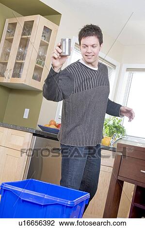 Stock Image - Man tossing can into recycling gin, Winnipeg, Canada. Fotosearch