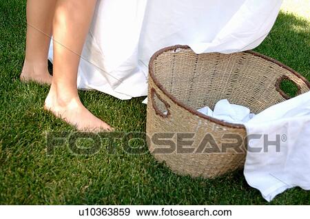 Stock Photo - Woman's feet in grass with laundry basket, Regina, Saskatchewan. Fotosearch