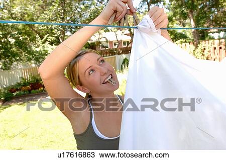 Stock Image - Young woman hanging laundry, Regina, Saskatchewan. Fotosearch