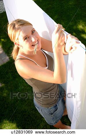 Stock Photo - Young woman hanging laundry, Regina, Saskatchewan. Fotosearch