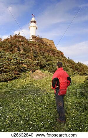 Stock Image - View Hiker and Lobster Cove Head Lighthouse at sunset, Gros Morne NP, Newfoundland, Canada. Fotosearch