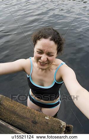 Picture - Woman (20-25) climbing down a ladder into a lake and making a face because the water is cold, Victoria, BC. Fotosearch