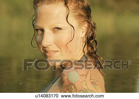 Stock Image - Woman with wet hair and tattoos in lake, Lake Katherine, Riding Mountain National Park, Manitoba, Canada. Fotosearch