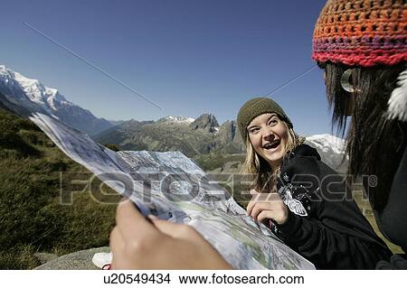 Picture - Young girls (19) reading a map in front of Mont Blanc, Col de Balme Chamonix, France. Fotosearch