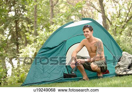 Stock Photo - Young man w/tattoo in front of tent, Regina, Saskatchewan. Fotosearch