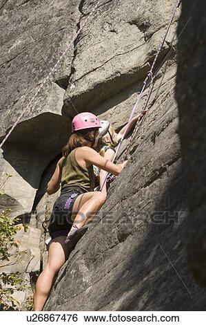 Stock Photograph - Young woman climbing with daughter (age 7) up granite cliff at Stone Hills near Rexford, Montana, USA. Fotosearch