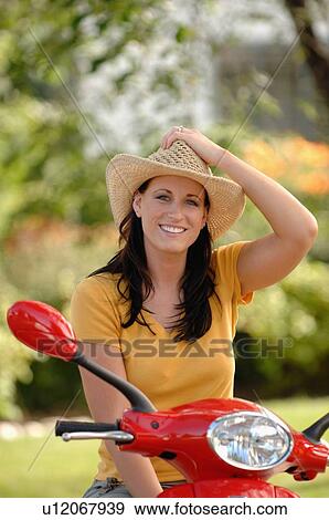 Stock Photo - Young woman on red vespa with cowboy hat, Regina, Saskatchewan. Fotosearch