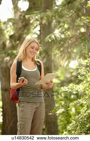 Stock Image - Young woman with gps type device and map in woods, Regina, Saskatchewan. Fotosearch